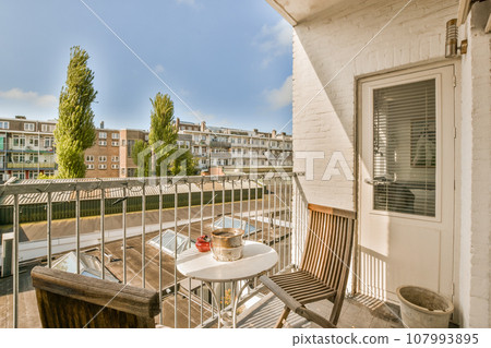 a balcony with an outside table and chairs on the left side, there is a blue sky in the background a balcony with an outside table and chairs on the left side, there is a blue sky in the background 107993895