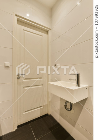 a white bathroom with black tile flooring and an open door leading to the toilet area in the shower room 107993928
