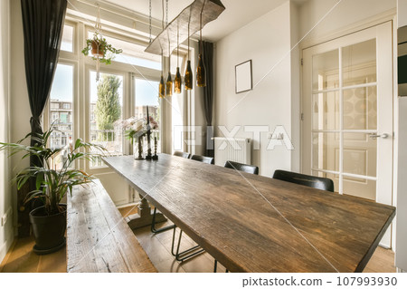 a dining room with a wooden table and chairs in front of an open door that leads to the balcony area a dining room with a wooden table and chairs in front of an open door that leads to the balcony area 107993930