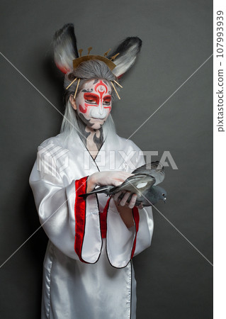 Rabbit woman with creative Halloween makeup hugging bird pigeon on blackboard background Rabbit woman with creative Halloween makeup hugging bird pigeon on blackboard background 107993939