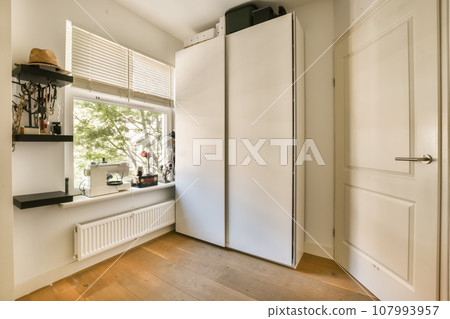 a room with a white door and some shelves on the wall behind it is a window that looks out onto the street 107993957