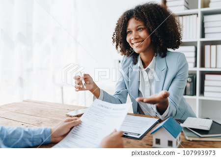 Real estate african american are delivering keys and houses to customers after agreeing to make a home purchase agreement and make a loan agreement or insurance. Real estate african american are delivering keys and houses to customers after agreeing to make a home purchase agreement and make a loan agreement or insurance. 107993973