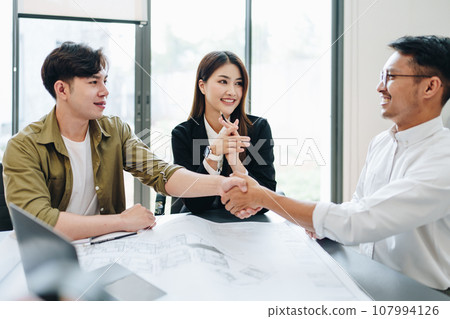 Engineers, designers and interior designers are handshake shack hands deal finalizing the design of interiors by discussing selecting materials and colors to design rooms to present to clients Engineers, designers and interior designers are handshake shack hands deal finalizing the design of interiors by discussing selecting materials and colors to design rooms to present to clients 107994126