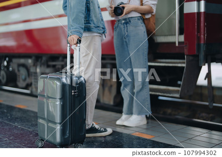 Tourist couples showing their love and happiness in a sweet way while waiting for their journey at the train station 107994302