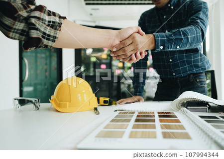 Engineers, designers and interior designers are handshake shack hands deal finalizing the design of interiors by discussing selecting materials and colors to design rooms to present to clients Engineers, designers and interior designers are handshake shack hands deal finalizing the design of interiors by discussing selecting materials and colors to design rooms to present to clients 107994344