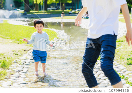 Child playing in the stream with his father Child playing in the stream with his father 107994526