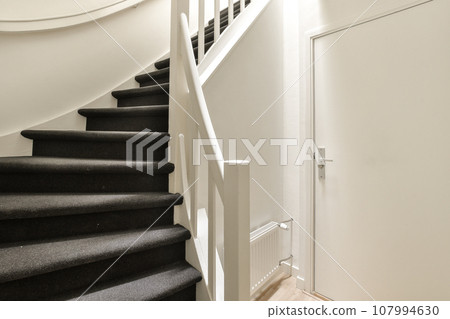 a staircase with black carpet and white trim on the stairs leading up to the second floor in an apartment building 107994630