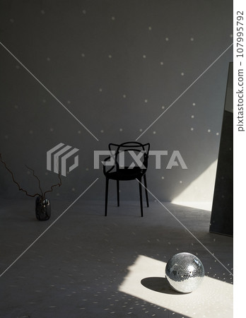 Glare on a white wall, a black chair, a disco ball and a large mirror. A world of fantasy 107995792