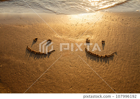 two emoticon happy smile face painted on jetted beach sand by sea 107996192