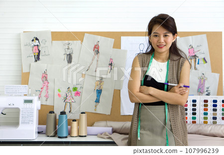 Talented Asian fashion designer showcasing her creative skills in a stunning display of craftsmanship. Talented Asian fashion designer showcasing her creative skills in a stunning display of craftsmanship. 107996239