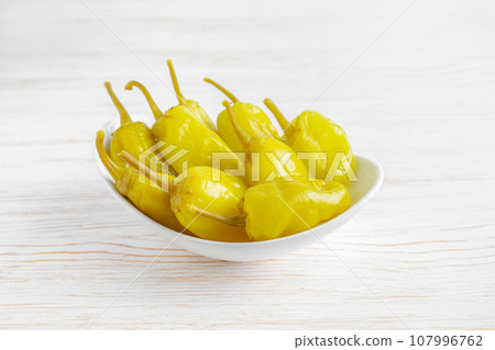 Pickled yellow greek pepper, pepperoncini or friggitelli in bowl on white wooden background 107996762