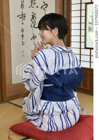 A young woman wearing a yukata sitting in a Japanese-style room in an old folk house A young woman wearing a yukata sitting in a Japanese-style room in an old folk house 107998072