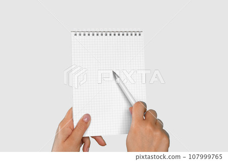 Female Hand Holding Notepad with Blank Page Isolated On Gray Neutral Studio Background. Close Up. Chroma Key Screen. Woman's Hand with Empty Card Paper MockUp. Advertisement gesture. Notebook Mock Up. Female Hand Holding Notepad with Blank Page Isolated On Gray Neutral Studio Background. Close Up. Chroma Key Screen. Woman's Hand with Empty Card Paper MockUp. Advertisement gesture. Notebook Mock Up. 107999765