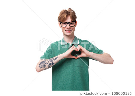 young smiling european guy with red hair in glasses shows a heart with his hands 108000155