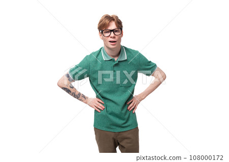 young surprised man with red hair in a green t-shirt on a white background with copy space 108000172