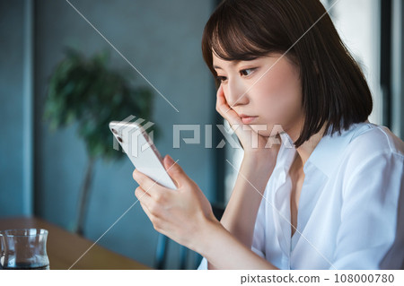 Young business woman looking at smartphone and thinking 108000780