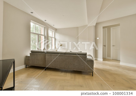 a living room with wood flooring and a television set on the wall in front of the couch is empty 108001334