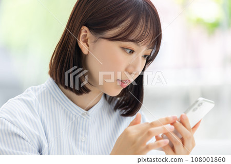 Young business woman operating a smartphone Young business woman operating a smartphone 108001860