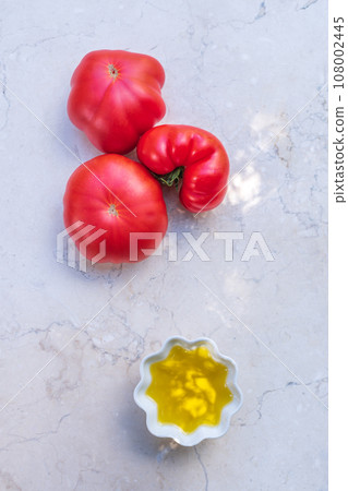 Olive oil and tomatoes on limestone table. Olive oil and tomatoes on limestone table. 108002445