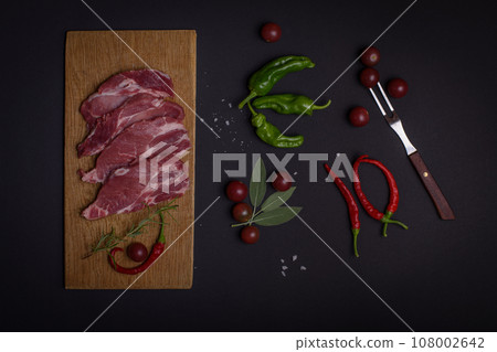 pork meat and vegetables on black background pork meat and vegetables on black background 108002642