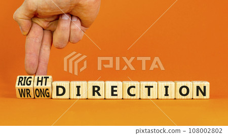 Right or wrong direction symbol. Concept words Right direction Wrong direction on wooden blocks. Beautiful orange background. Businessman hand. Business right or wrong direction concept. Copy space. Right or wrong direction symbol. Concept words Right direction Wrong direction on wooden blocks. Beautiful orange background. Businessman hand. Business right or wrong direction concept. Copy space. 108002802