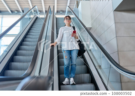 Middle-aged woman with backpack in casual style on escalator 108003502