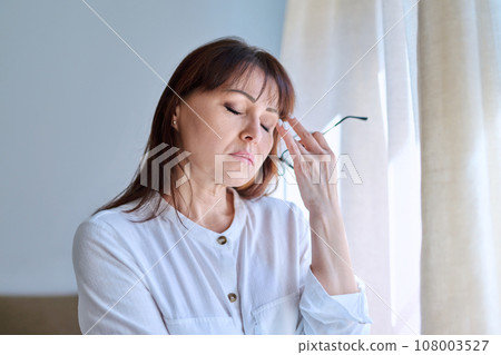 Middle-aged woman experiencing stress, difficulties, headache Middle-aged woman experiencing stress, difficulties, headache 108003527