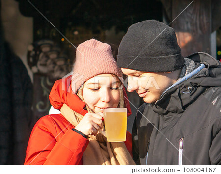 Happy couple drinking hot mulled wine and smiling at Christmas market. Merry Christmas. New Year. Happy couple drinking hot mulled wine and smiling at Christmas market. Merry Christmas. New Year. 108004167