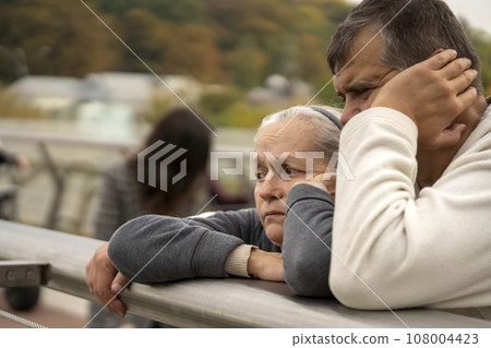 An elderly man and a woman with sad faces outdoor. 108004423