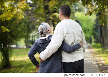 An elderly couple, man and woman walk in the autumn park. 108004424