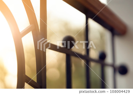 Curved forged modern fence on the balcony closeup. Curved forged modern fence on the balcony closeup. 108004429