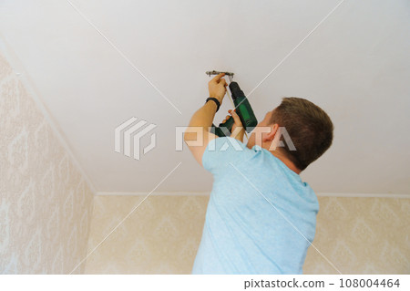 A man is working on the installation of a ceiling luminaire on the ceiling. 108004464