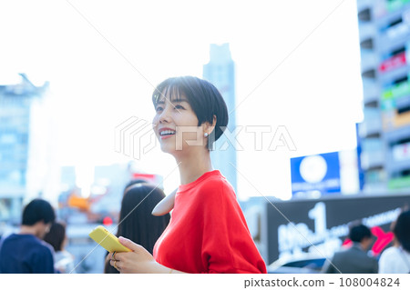 一個女人帶著智能手機在城市裡散步 一個女人帶著智能手機在城市裡散步 108004824