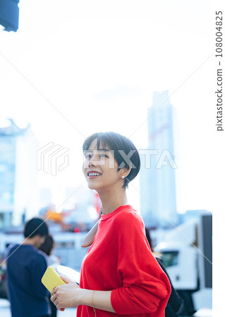 一個女人帶著智能手機在城市裡散步 一個女人帶著智能手機在城市裡散步 108004825