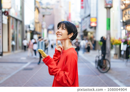 A woman who uses a smartphone in the city 108004904