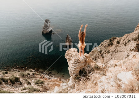 Woman travel sea. Happy tourist enjoy taking picture outdoors for memories. Woman traveler looks at the edge of the cliff on the sea bay of mountains, sharing travel adventure journey Woman travel sea. Happy tourist enjoy taking picture outdoors for memories. Woman traveler looks at the edge of the cliff on the sea bay of mountains, sharing travel adventure journey 108007011