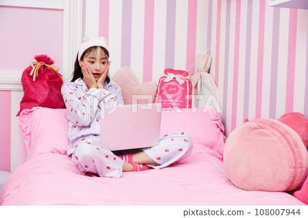 Young woman relaxing in colorful bedroom 108007944
