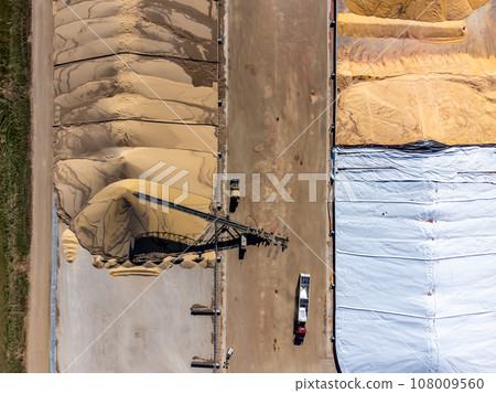 Drone view over grain storage piles being filled and covered 108009560