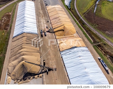 Drone view over grain storage piles being filled and covered 108009679