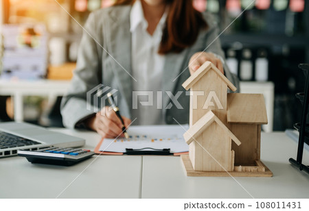 Real estate broker agent presenting and consult to customer to decision making sign insurance form agreement, home model, concerning mortgage loan offer. 108011431