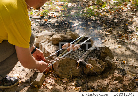 Man frying sausages on a fire Man frying sausages on a fire 108012345