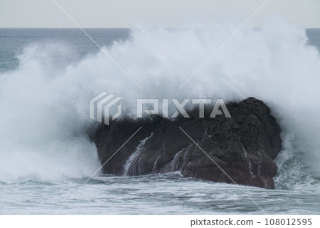 Splashing waves hitting a rock 108012595