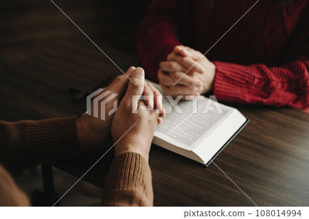 Two people reading and study bible in home and pray together.Studying the Word Of God With Friends. in sun light. 108014994