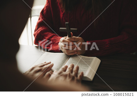 Two people reading and study bible in home and pray together.Studying the Word Of God With Friends. in sun light. 108015021