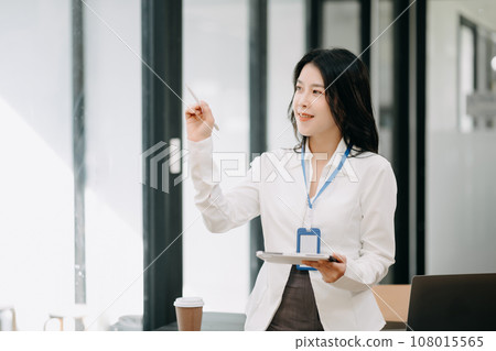 Successful Asian Businesswoman Analyzing Finance on Tablet and Laptop at Office Desk tax, report, accounting, statistics, and analytical research concept. Successful Asian Businesswoman Analyzing Finance on Tablet and Laptop at Office Desk tax, report, accounting, statistics, and analytical research concept. 108015565