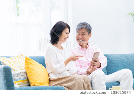 Senior couple with smartphones in the living room 108015974