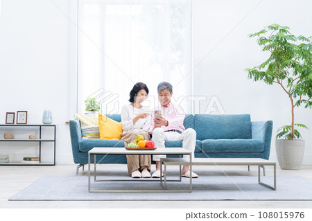 Senior couple with smartphones in the living room 108015976
