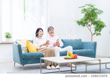 Senior couple with smartphones in the living room 108015978