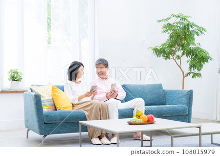 Senior couple with smartphones in the living room 108015979