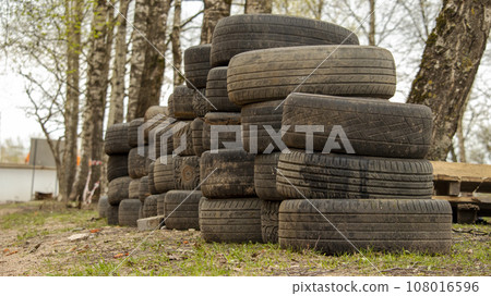 folded old car tires lie on the ground near the road folded old car tires lie on the ground near the road 108016596